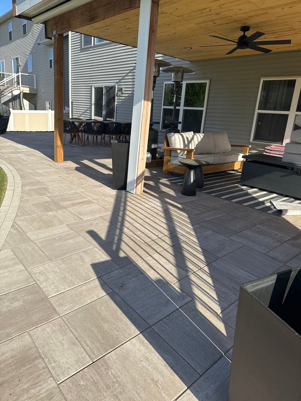 Modern patio with stylish furniture, stone tiles, and shaded seating area for relaxation.