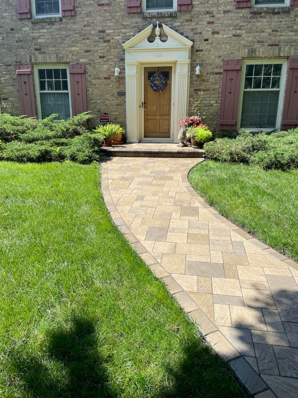 Curved stone pathway leading to a classic home entrance with decorative plants.